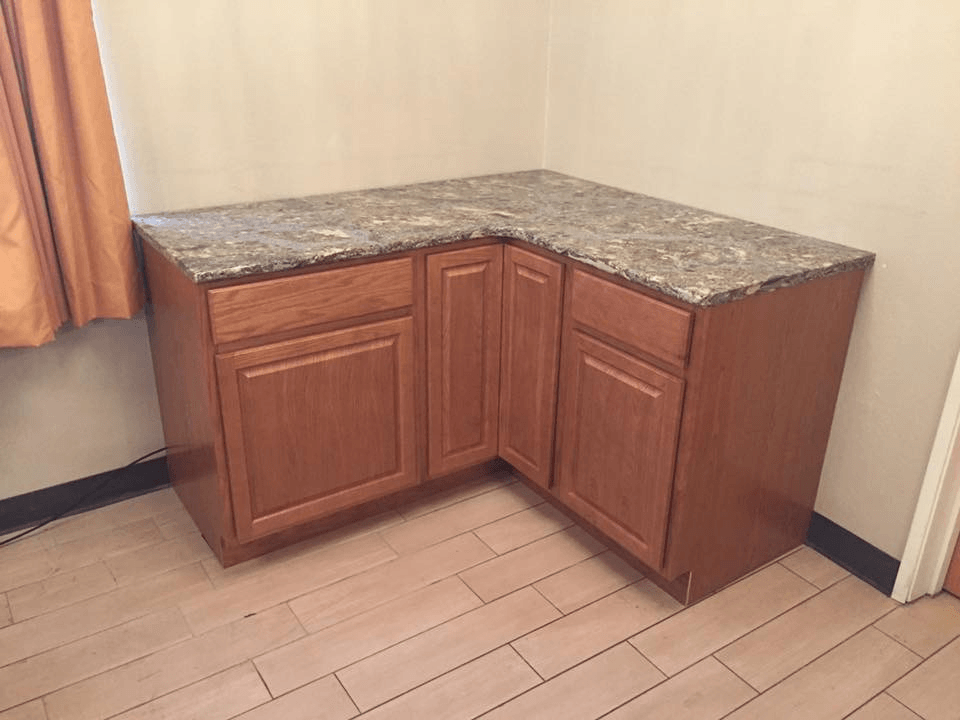 A corner of a kitchen with wooden cabinets and a granite counter top.