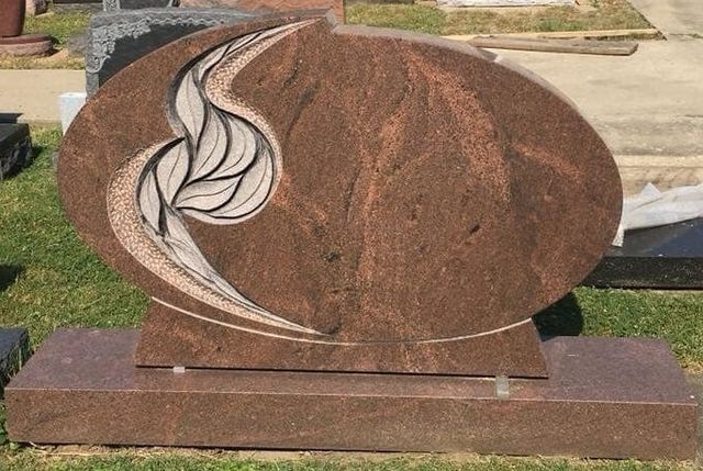 A gravestone in a cemetery with a leaf design on it