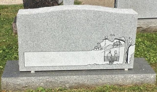 A gravestone with a picture of two people on it is in a cemetery.