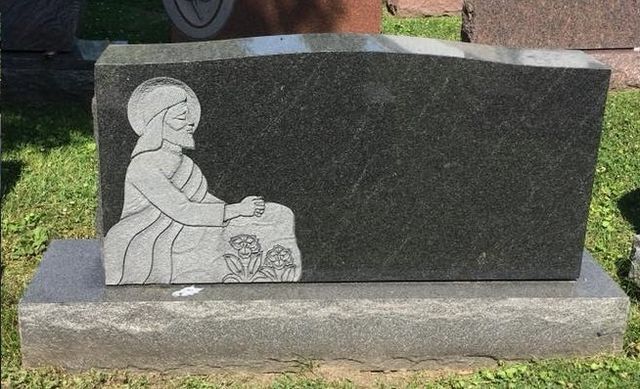 A gravestone with a statue of jesus on it in a cemetery.