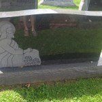 A gravestone with a statue of a woman sitting on it in a cemetery.