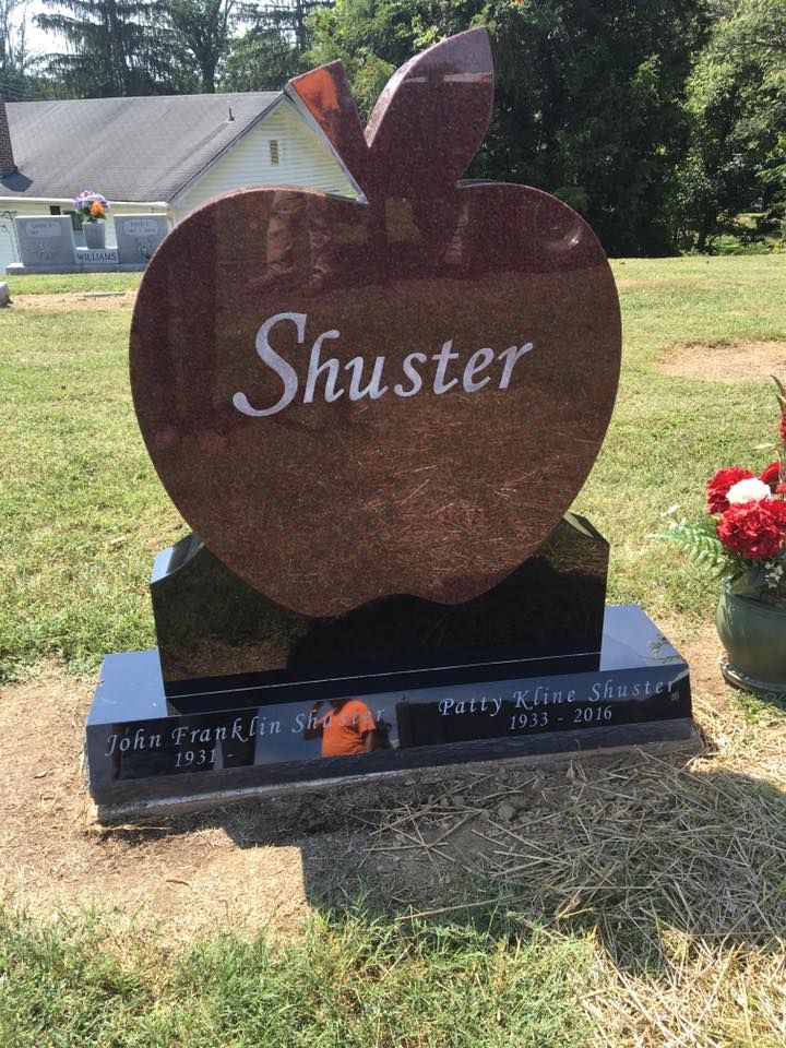 A gravestone for shuster in the shape of an apple