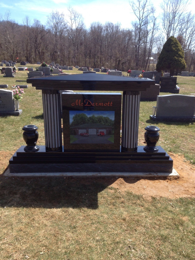 A grave in a cemetery with a picture of a house on it.
