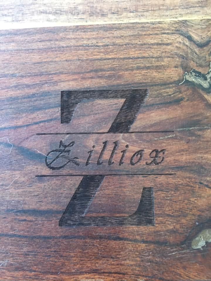 A close up of a wooden table with a monogram on it.