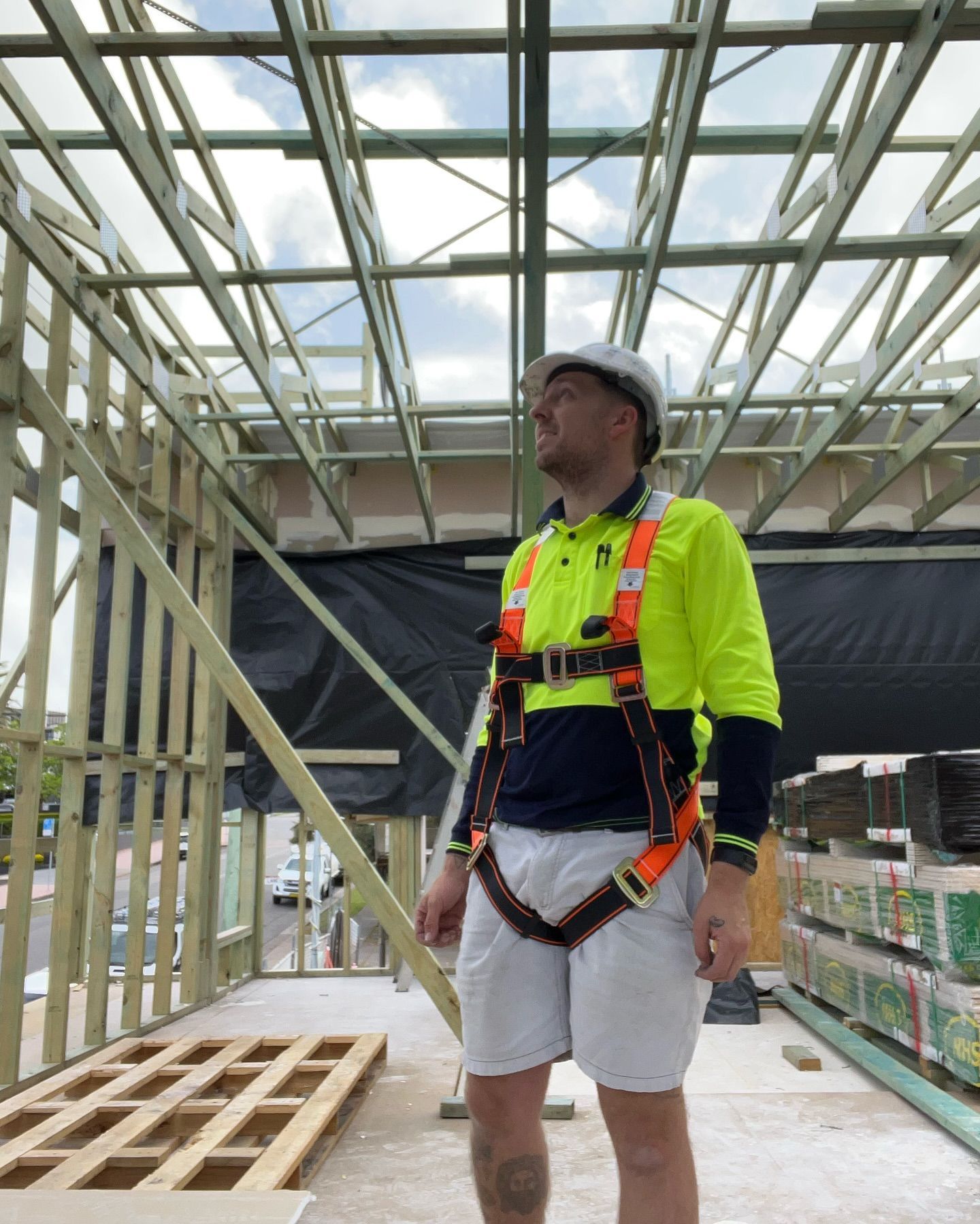Construction Worker in Safety Gear Looking Up at Wooden Roof Frame — Hunter Fire & Safety in Port Stephens, NSW