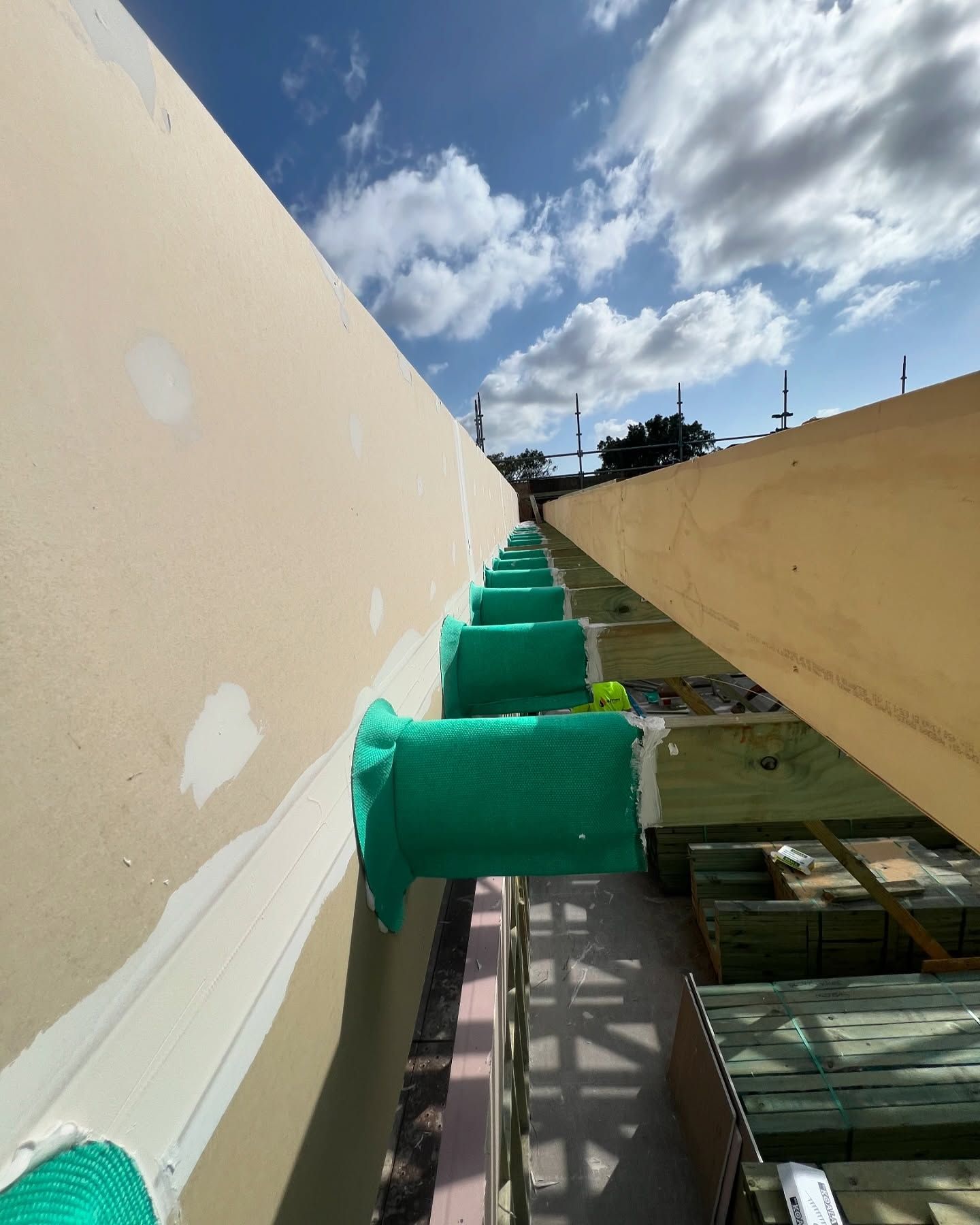 Green Mesh Wrapped Around Wooden Beams, Construction Site, Blue Sky — Hunter Fire & Safety in Lake Macquarie, NSW
