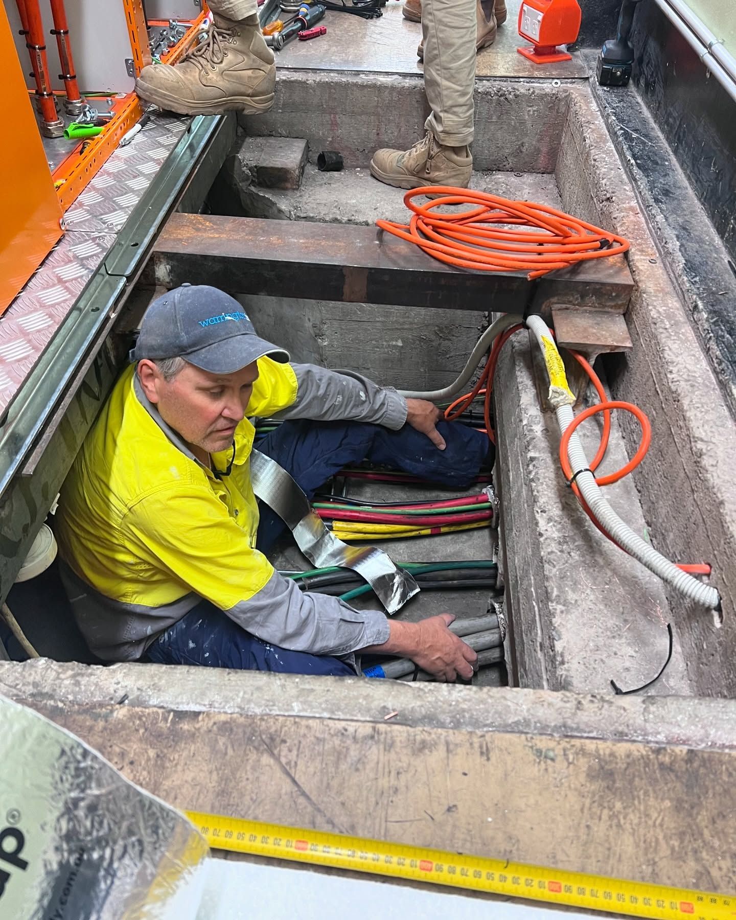Man in Work Clothes Works on Electrical Cables in a Concrete Conduit — Hunter Fire & Safety in Newcastle, NSW