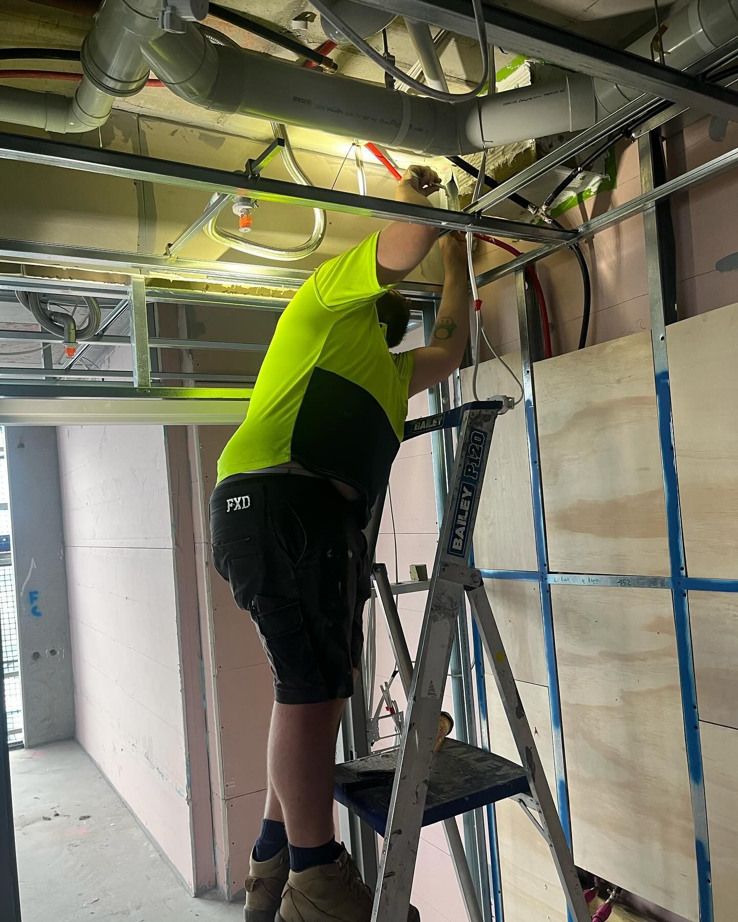 Construction Worker on Ladder Installing Ceiling Framework — Hunter Fire & Safety in Port Stephens, NSW