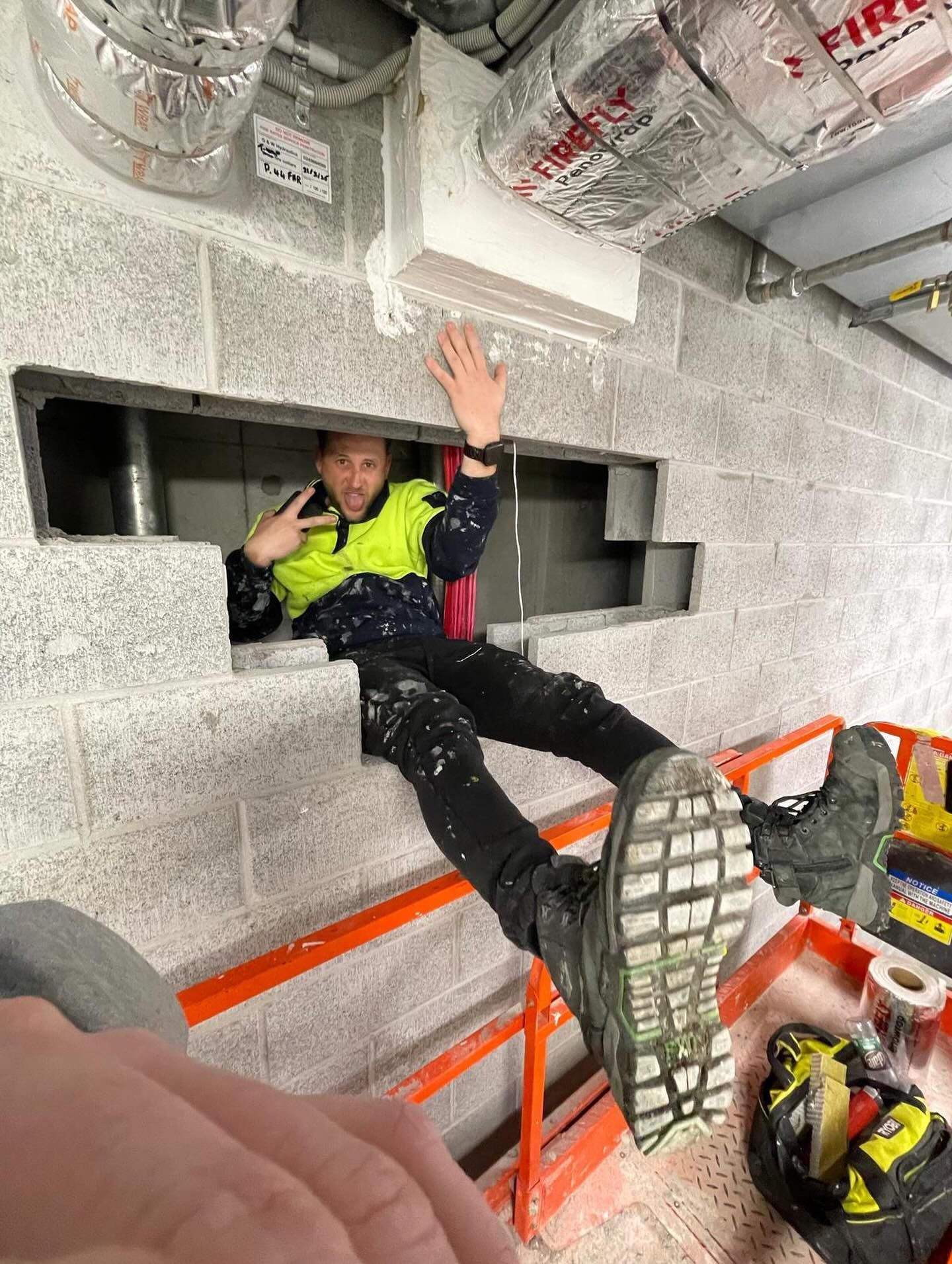Construction Worker in a Wall Opening, Gesturing — Hunter Fire & Safety in Edgeworth, NSW