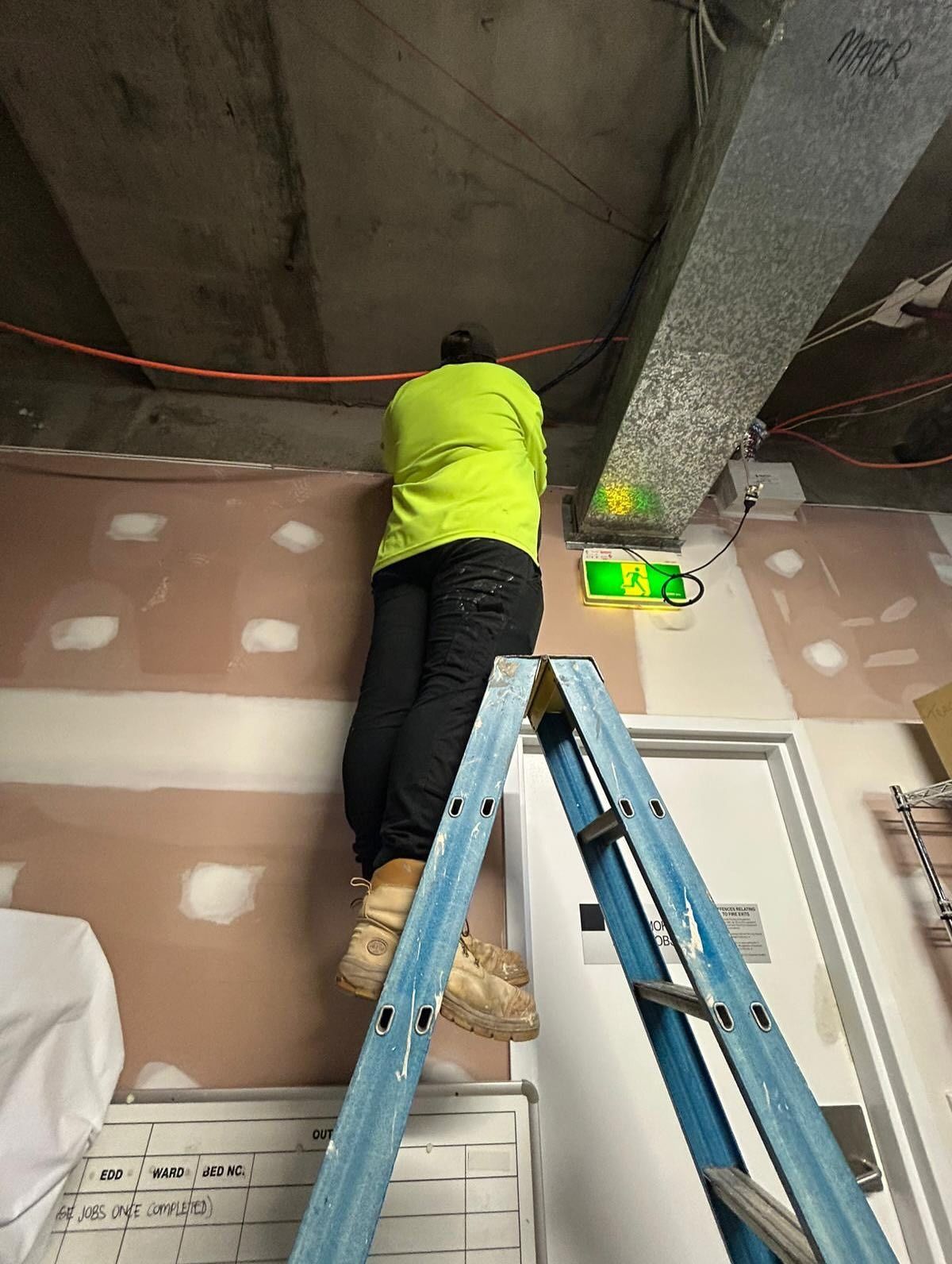 Person on Ladder Works on Ceiling Near a Ventilation Duct — Hunter Fire & Safety in Coffs Harbour, NSW