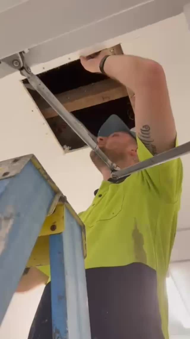 Man on Ladder Reaching Into Ceiling Opening — Hunter Fire & Safety in Port Macquarie, NSW