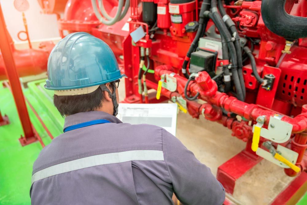 Person in a Blue Hard Hat Inspecting a Large Red Machine — Hunter Fire & Safety in Coffs Harbour, NSW