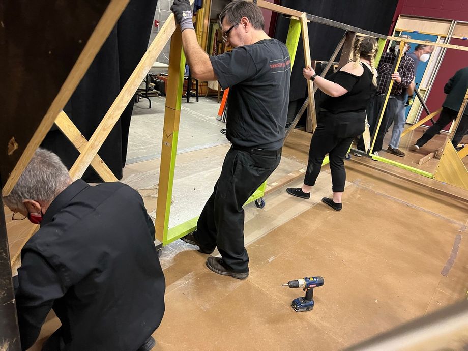 A group of people are working on a large mirror in a room.