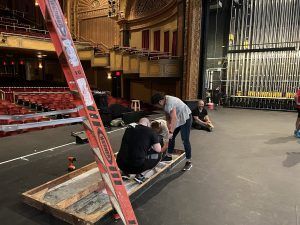 A group of people are working on a stage in a theater.