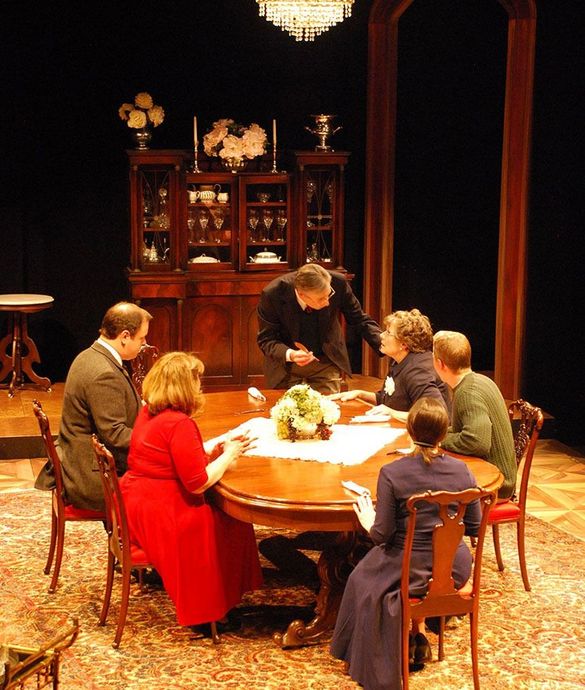 A group of people are sitting around a table in a dark room