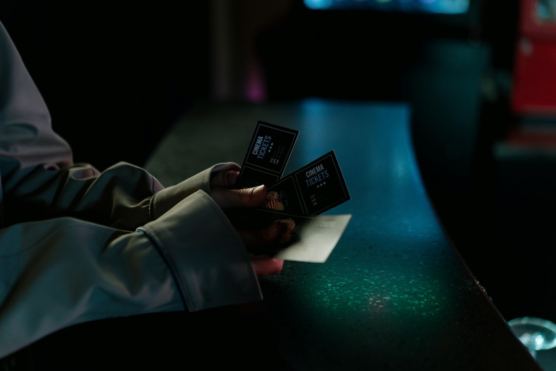 A person is holding two cards in their hands in a dark room.