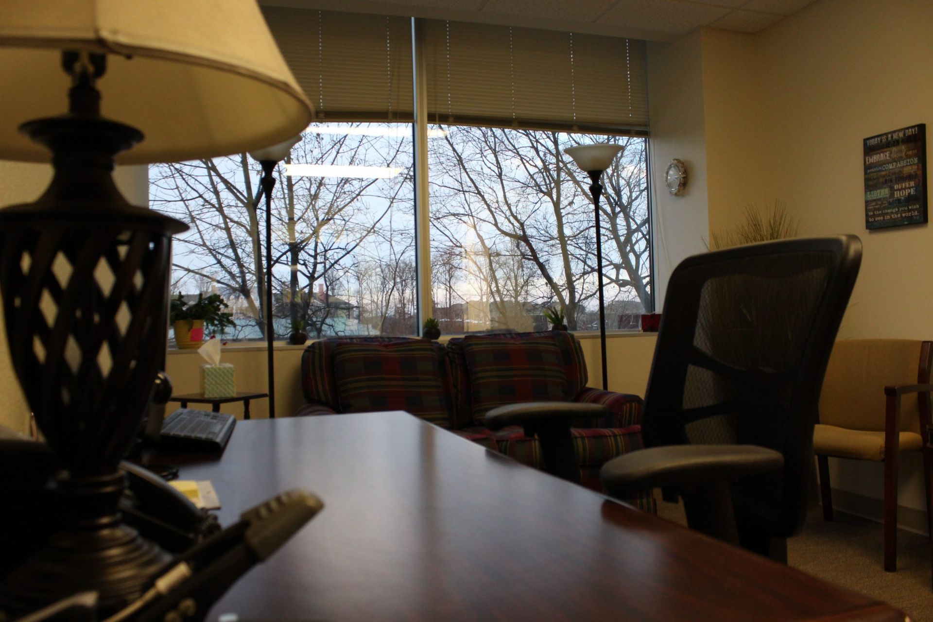 A lamp sits on a desk in front of a window