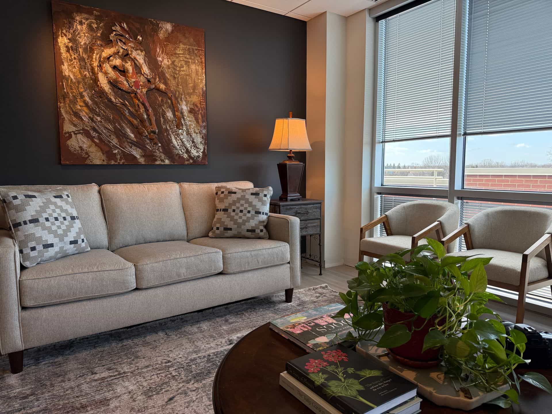 A living room with a couch , chairs , a table and a potted plant.
