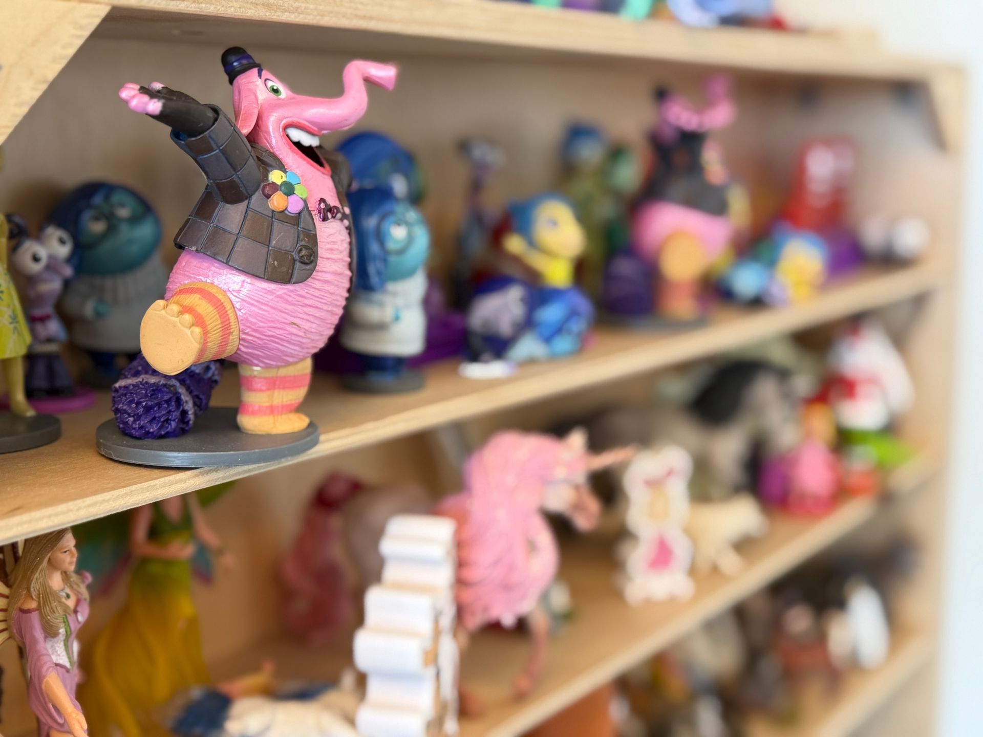 A shelf filled with lots of toys including a pink elephant for child therapy