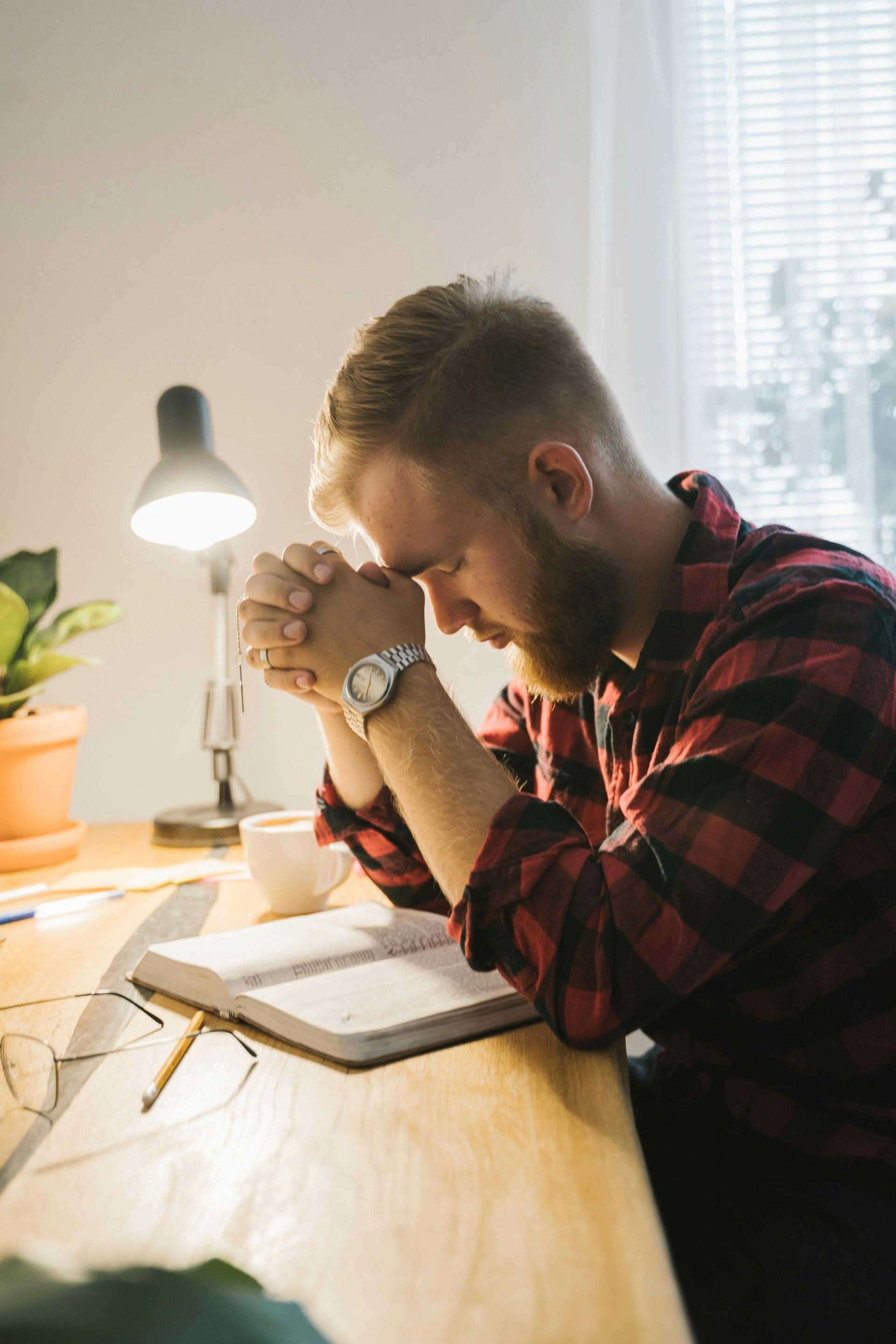 A man is sitting at a table with his hands folded in prayer in christian counseling