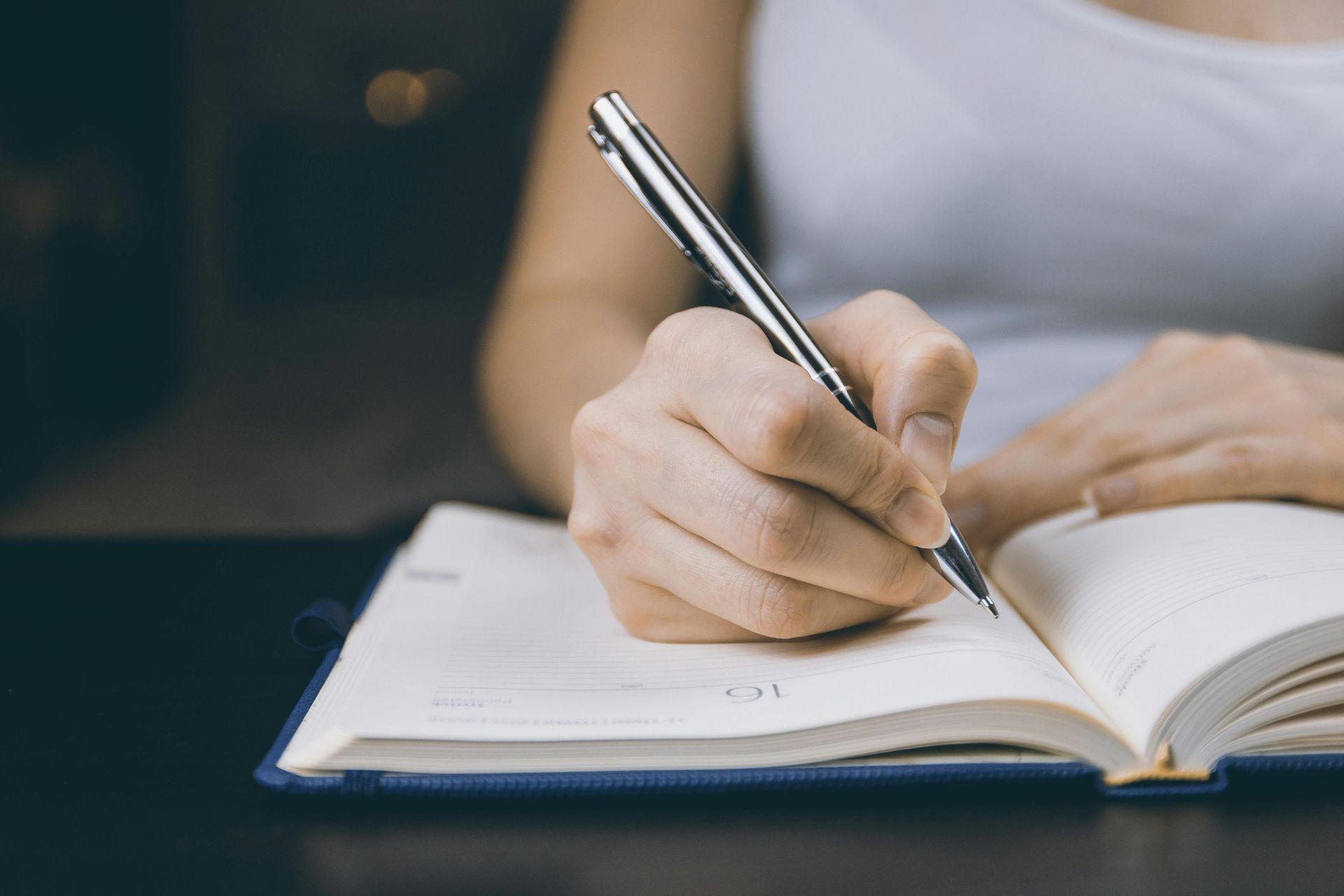 A woman is writing in a notebook with a pen in counseling office