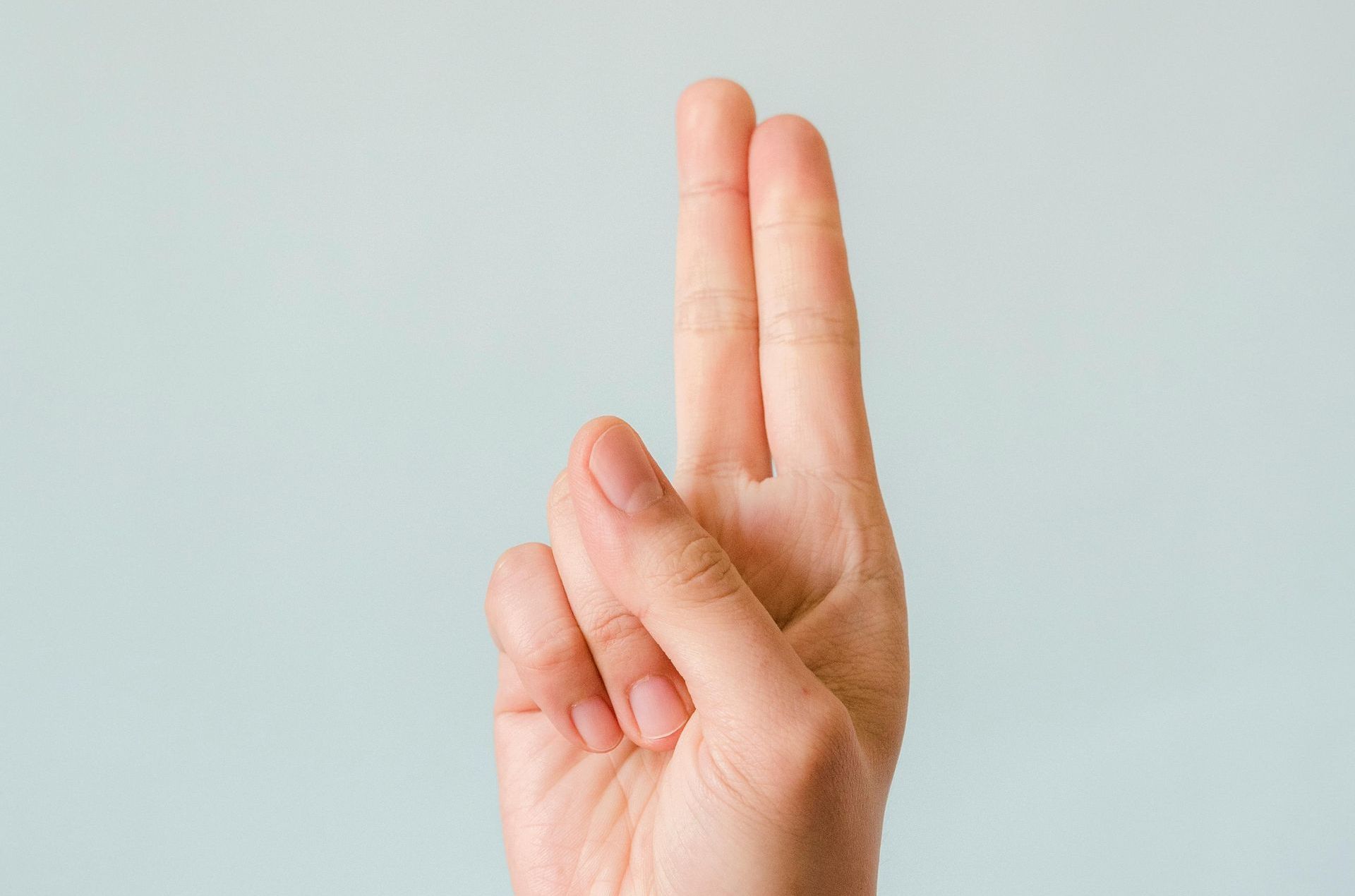 A close up of a person 's hand making a peace sign.