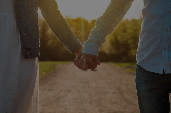 A married man and a woman are holding hands on a dirt road.