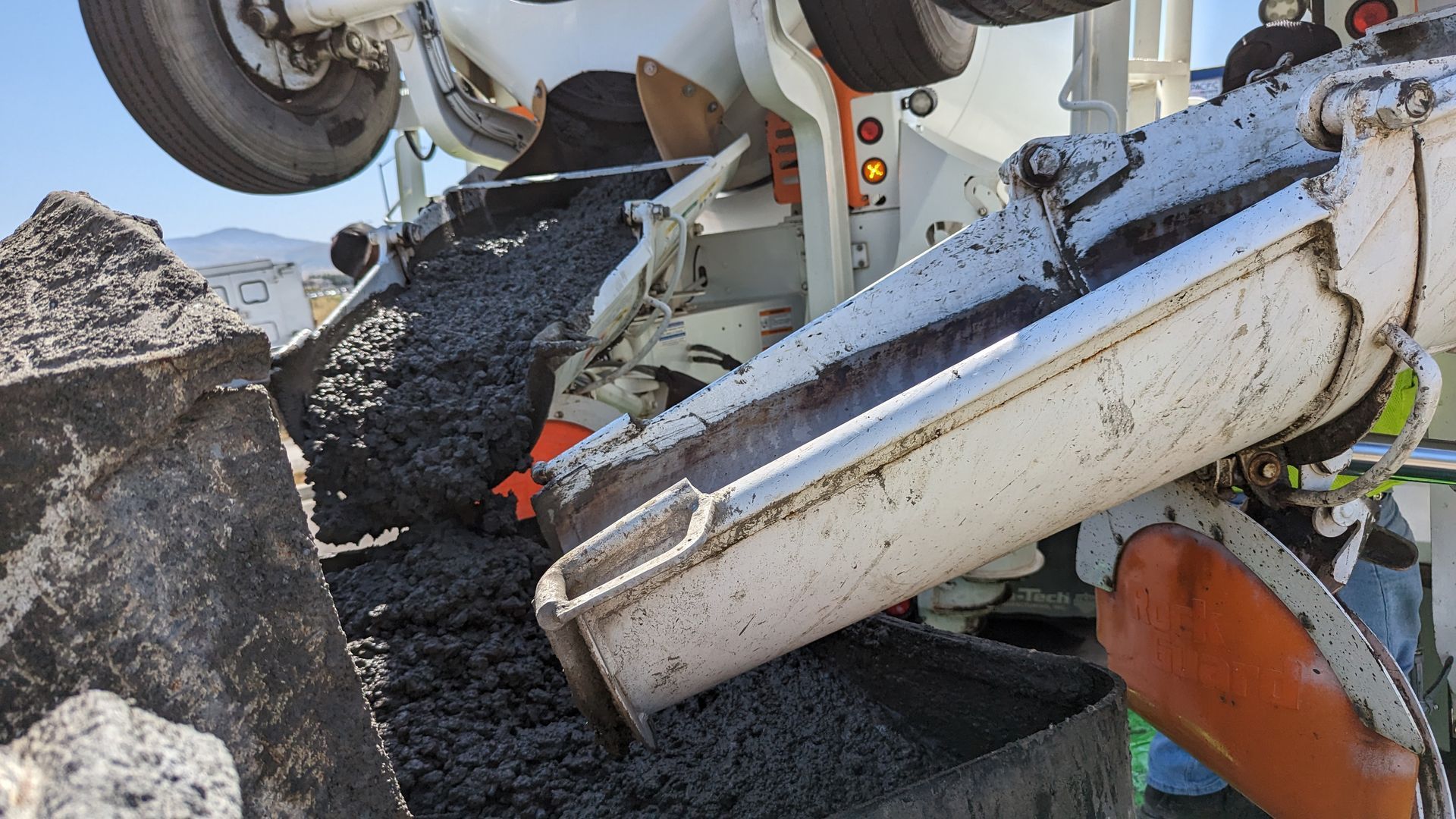 Two concrete trucks pouring concrete into a concrete pump.