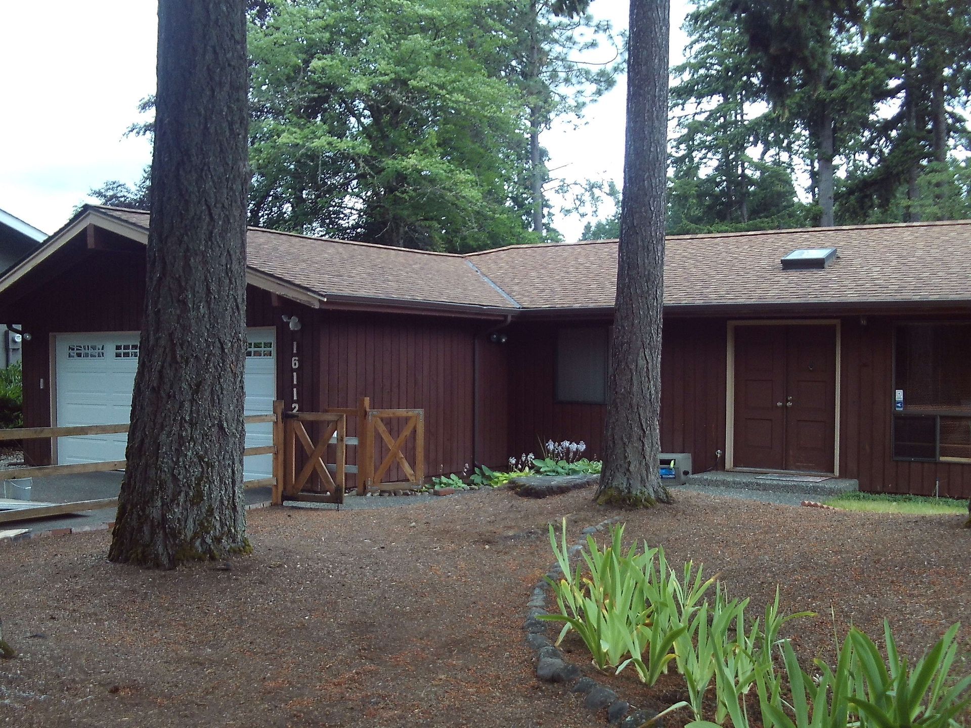 A house is surrounded by trees and has a white garage door