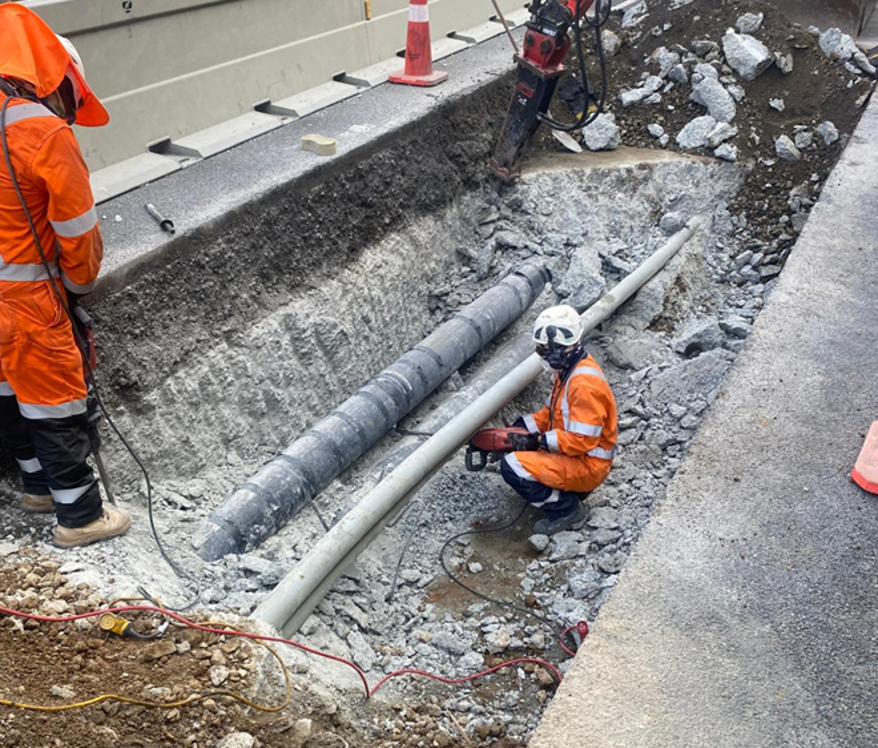 A group of construction workers are working on a pipe in the dirt.