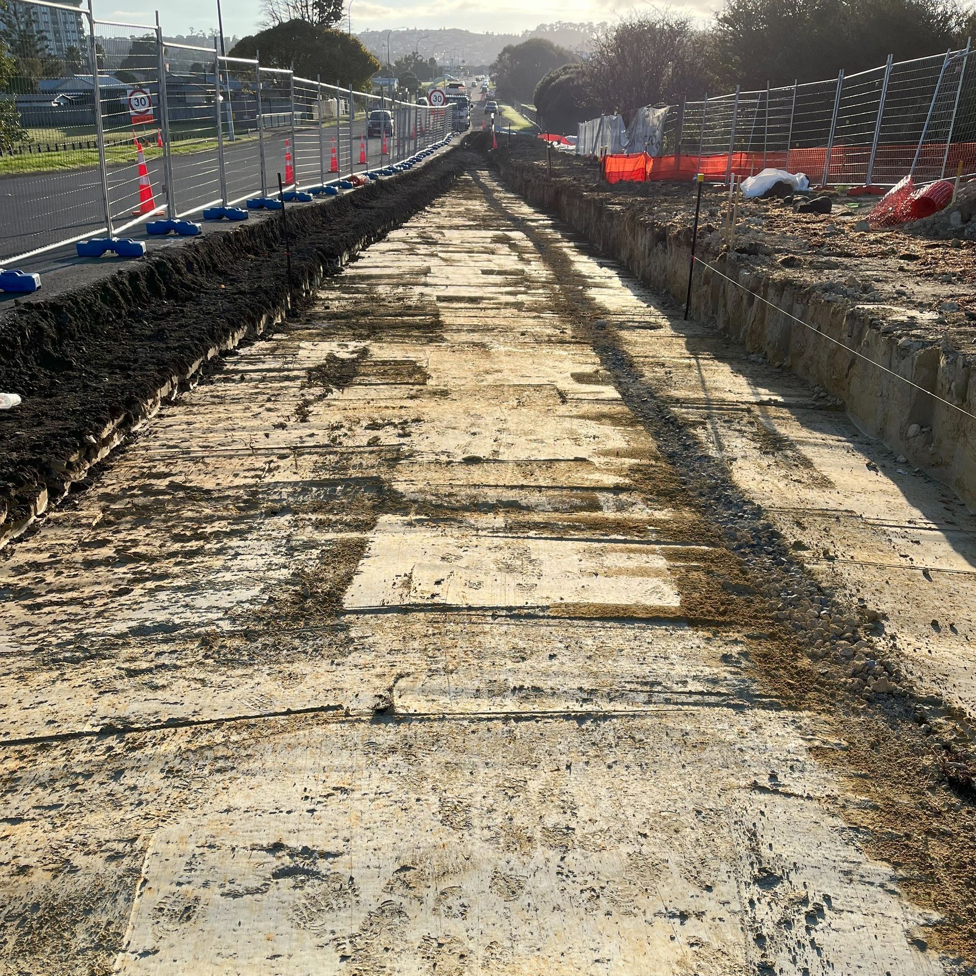 A muddy road with a fence in the background is being built.