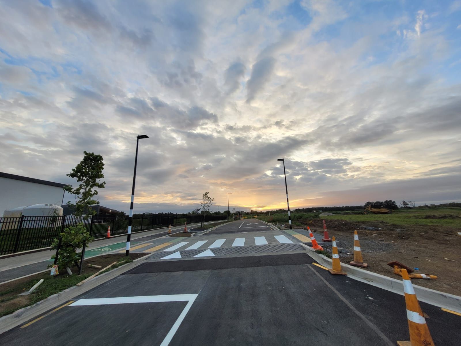 A road with a crosswalk and a sunset in the background.