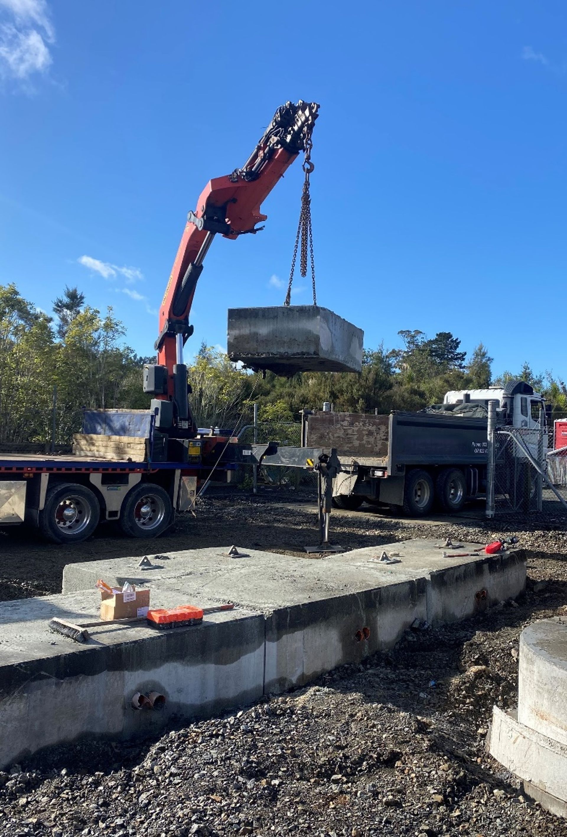 A crane is lifting a large piece of concrete into a dump truck.