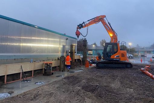 A large orange excavator is working on a construction site.