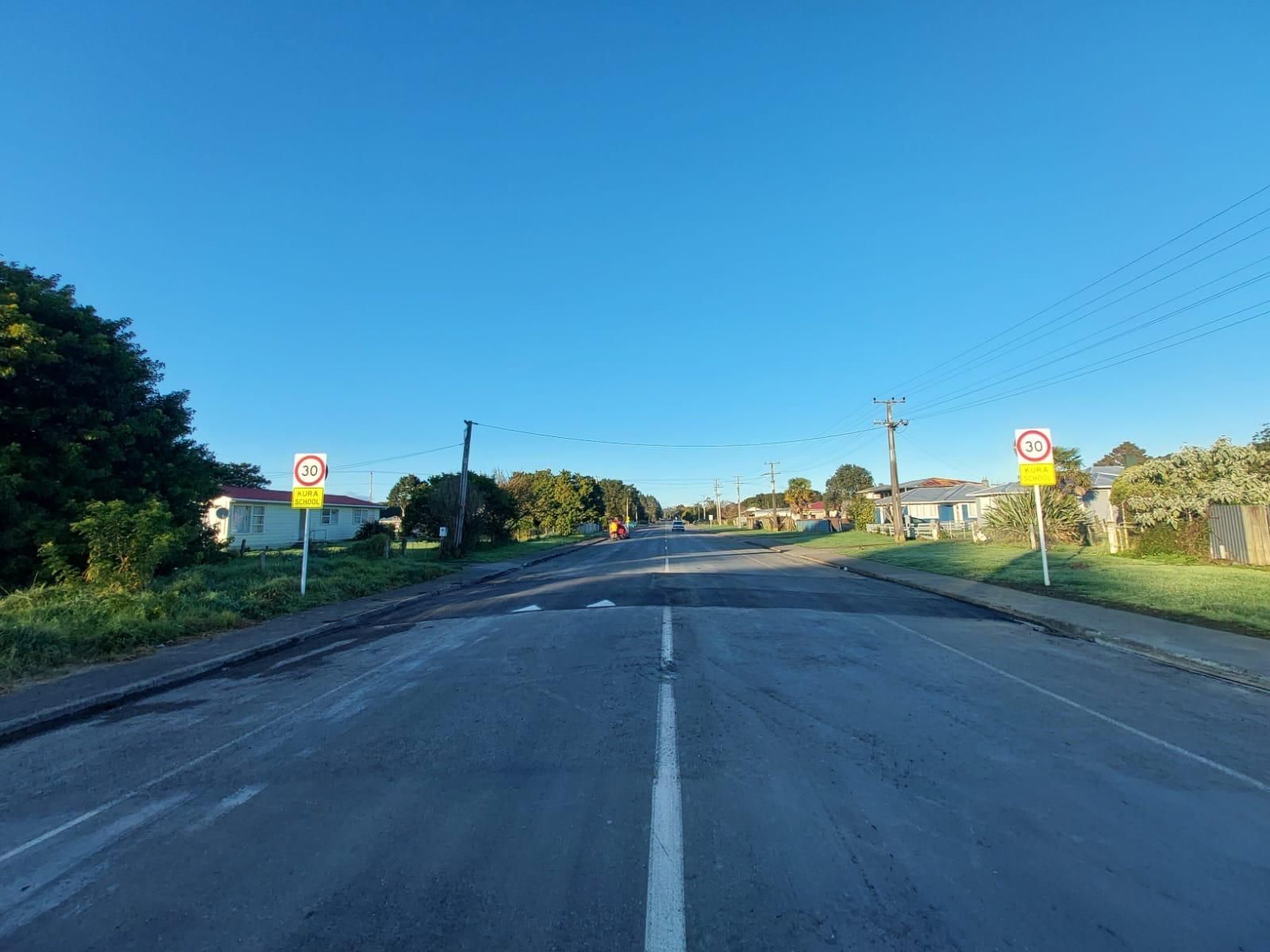A road with a lot of signs on it and a blue sky in the background.