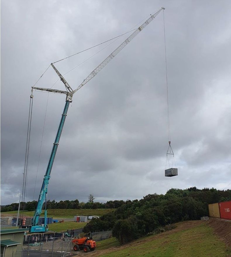 A large crane is lifting a container on a cloudy day