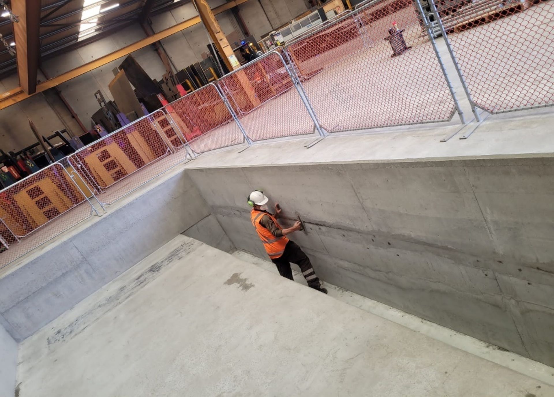 A man in a hard hat is working on a concrete wall.