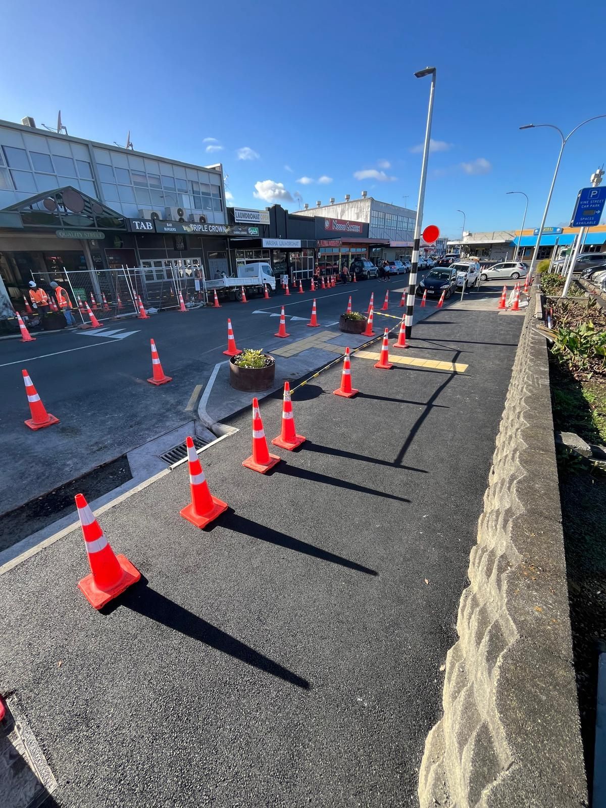 A row of orange and white traffic cones on the side of a road.