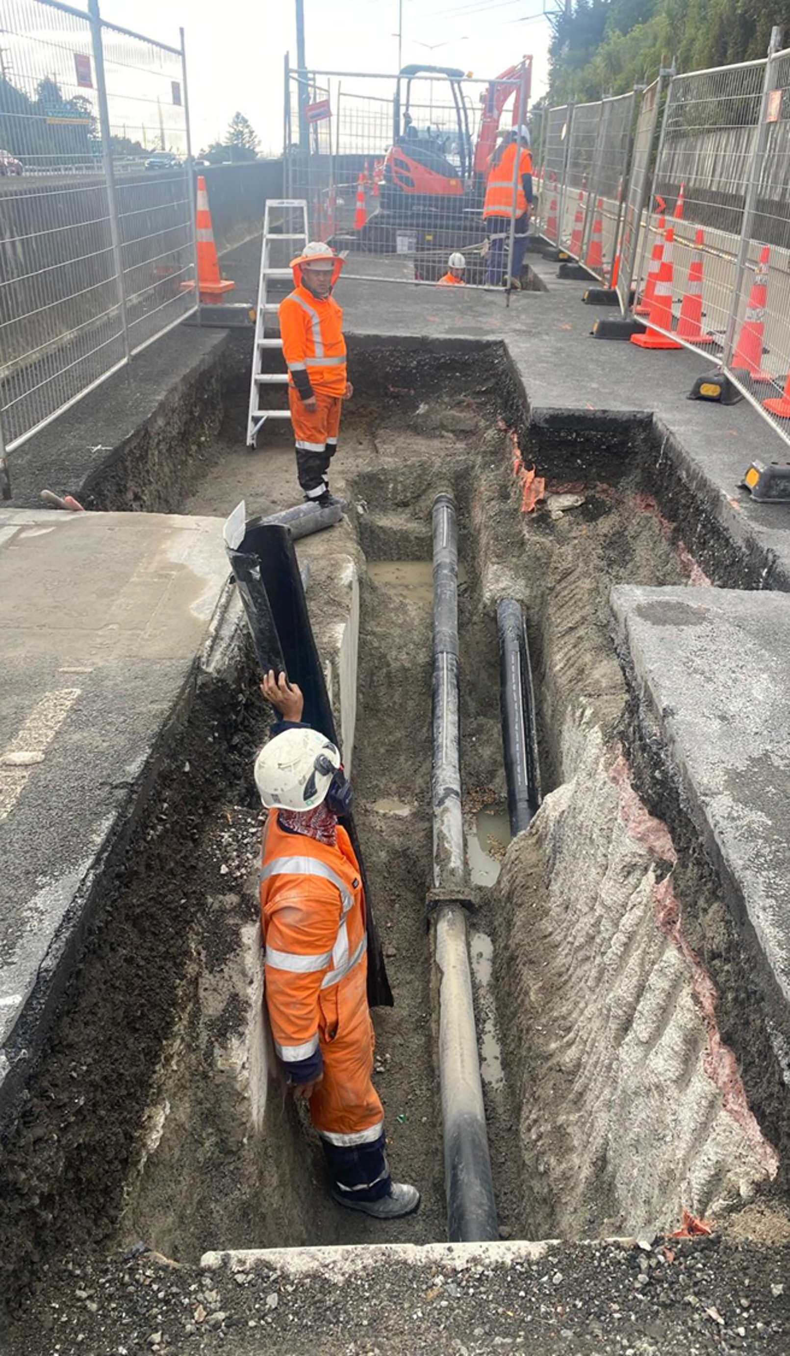 A group of construction workers are working in a trench.