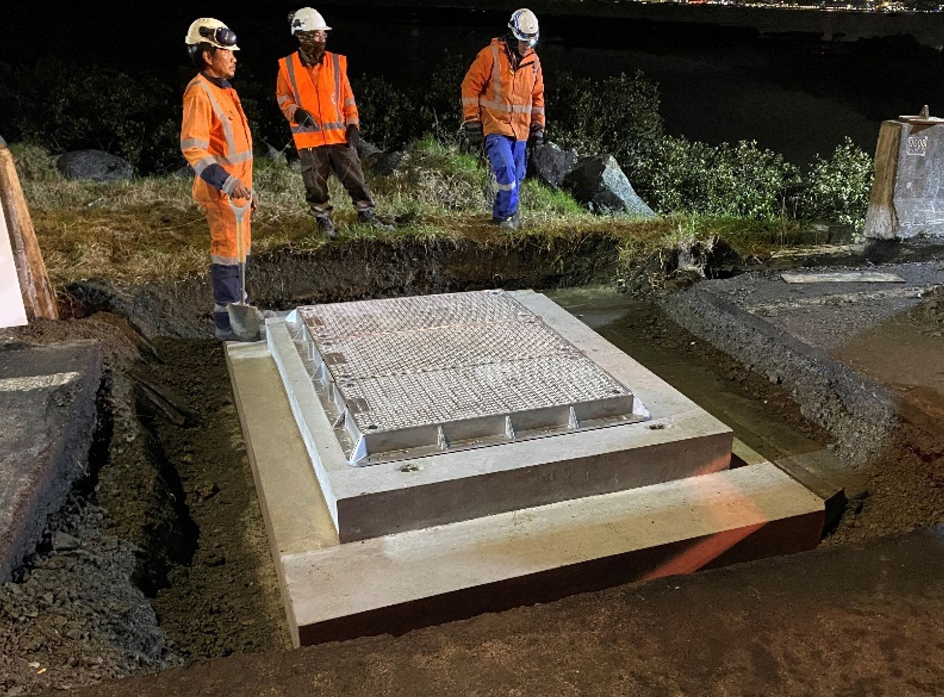 A group of construction workers are standing around a large concrete slab.