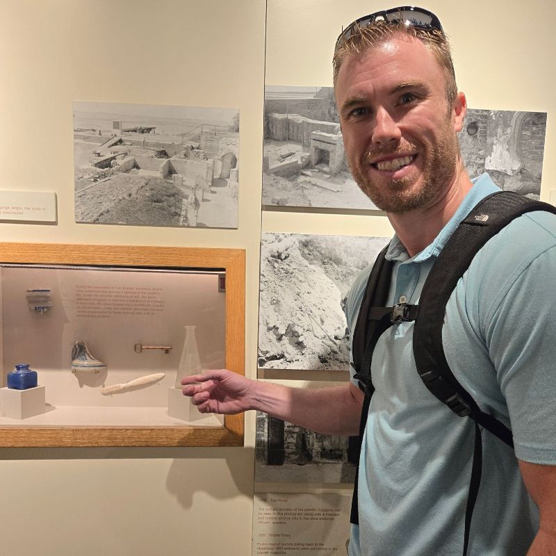 A man with a backpack is standing in front of a display case