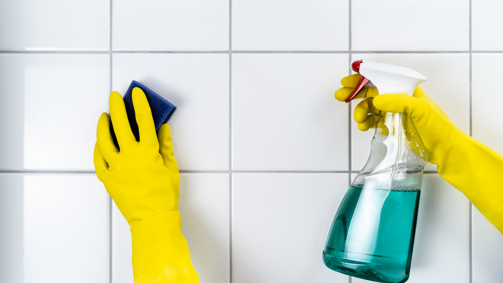 Tile and grout cleaning with eco-friendly spray and scrubbing sponge on white tile surface