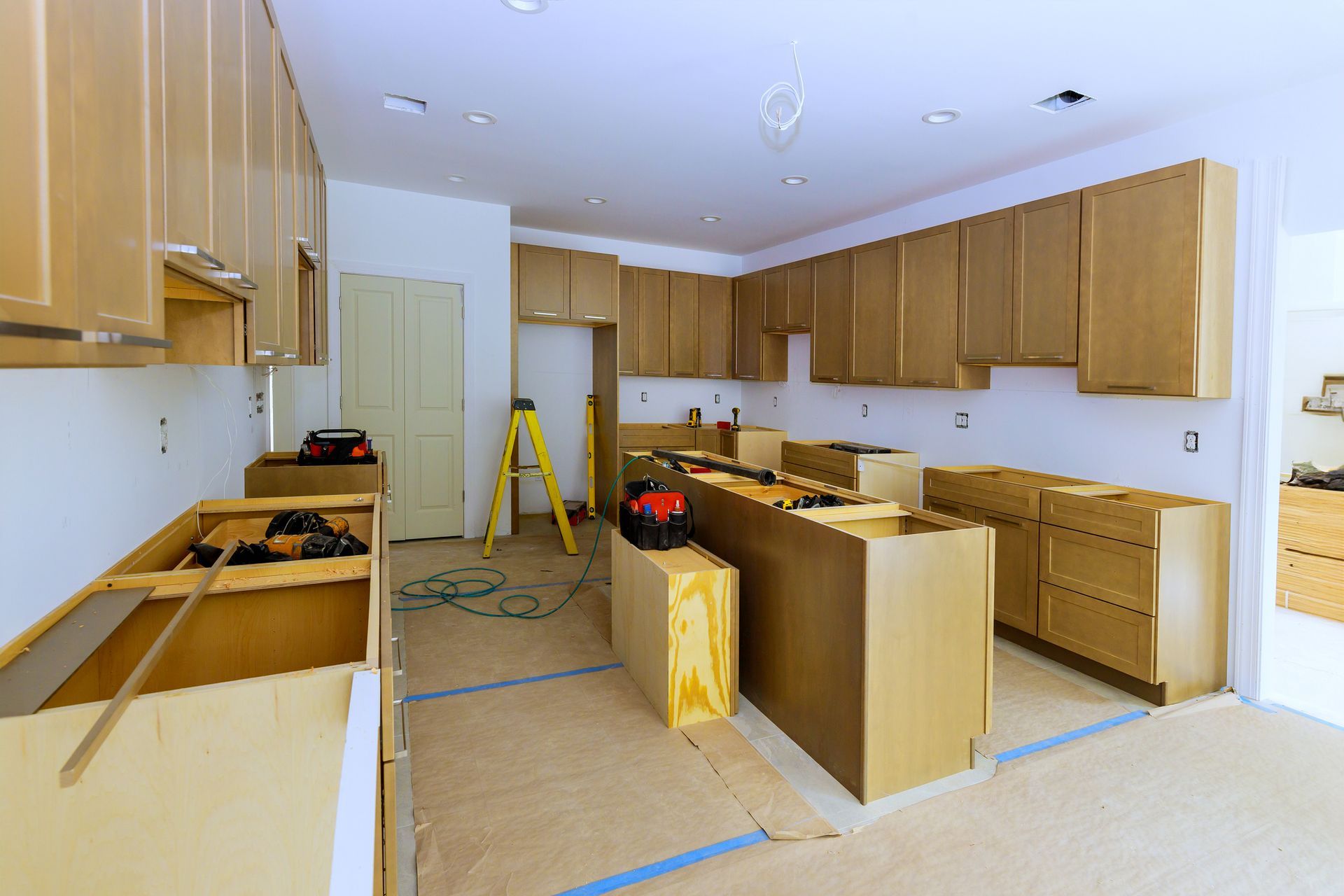 A kitchen under construction with wooden cabinets and a ladder.