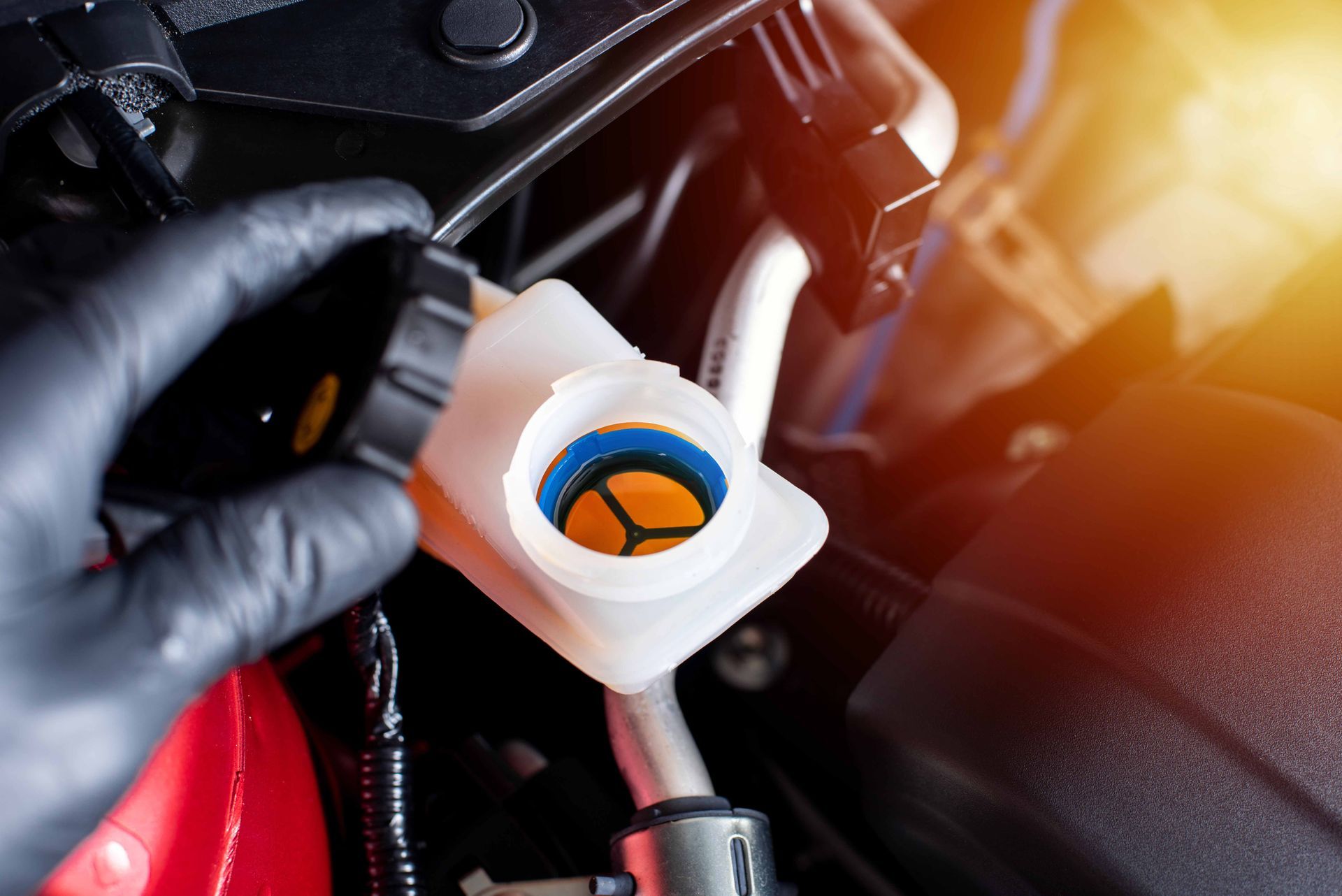 A close-up of a mechanic’s hand checking a car's brake fluid.