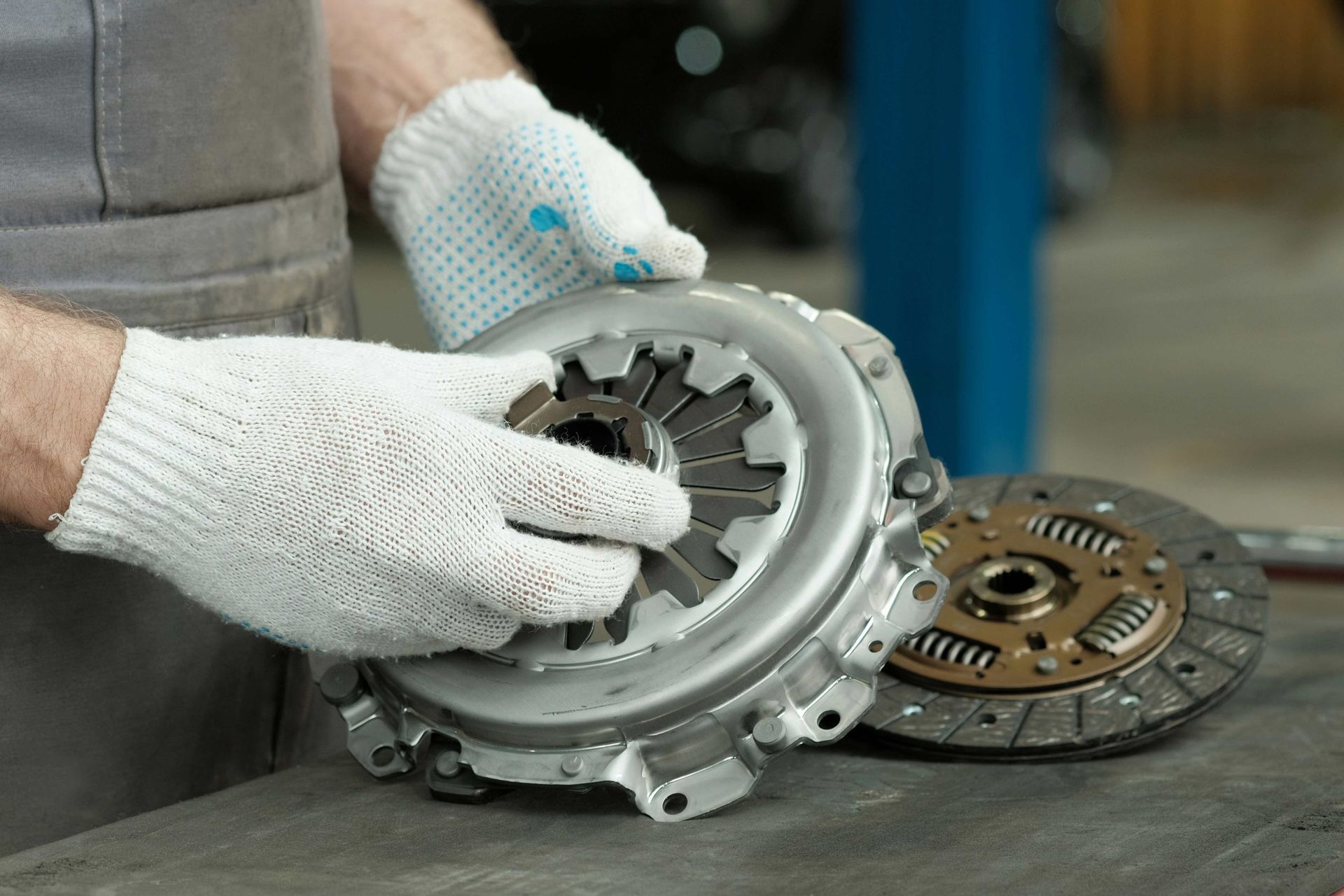 A close-up of the hands of a mechanic holding a new clutch kit.
