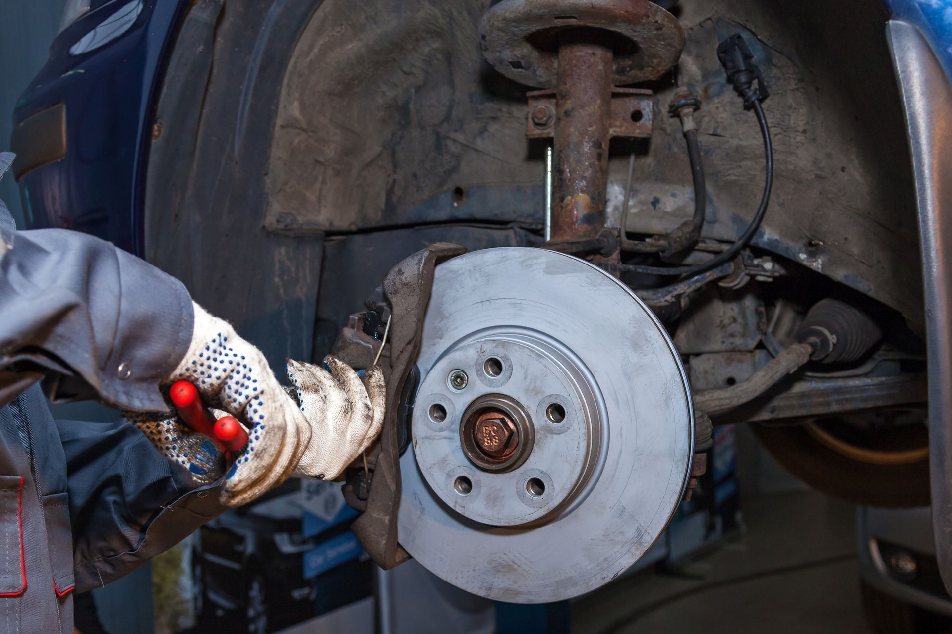 A person inspects a car engine with a clipboard and pen during a registration check.