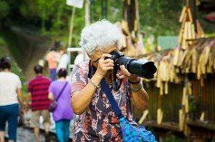 elderly woman holding a camera with a long lens
