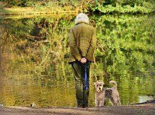 woman in barbour jacket with a dog by a river