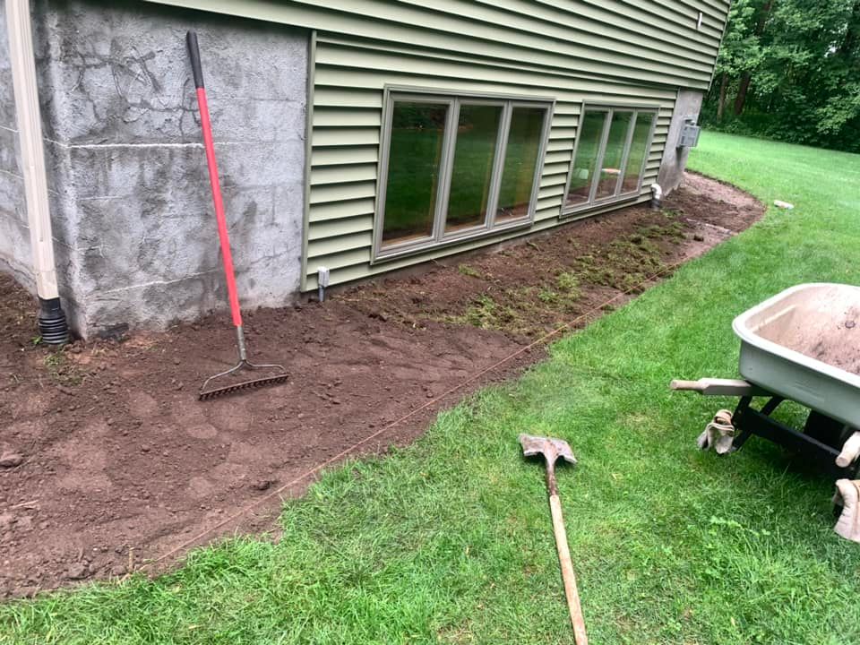 A wheelbarrow filled with dirt is sitting in front of a house.