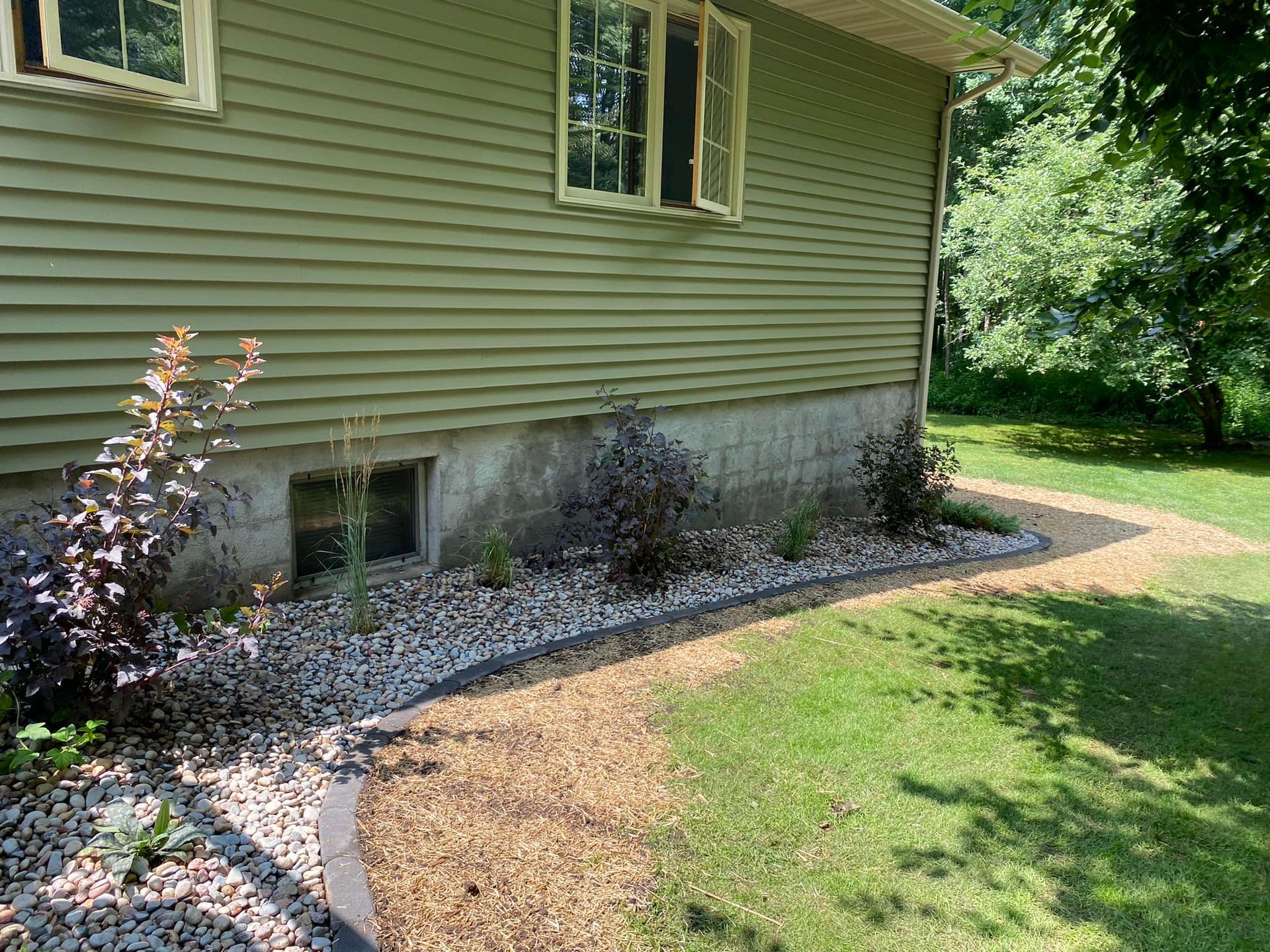 A green house with a gravel walkway leading to it.